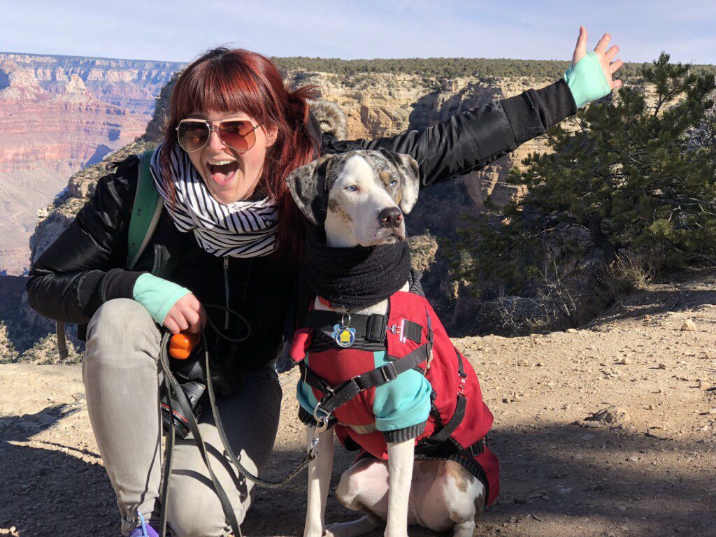 Carol posing with Mucca in their winter gear in front of the Grand Canyon.