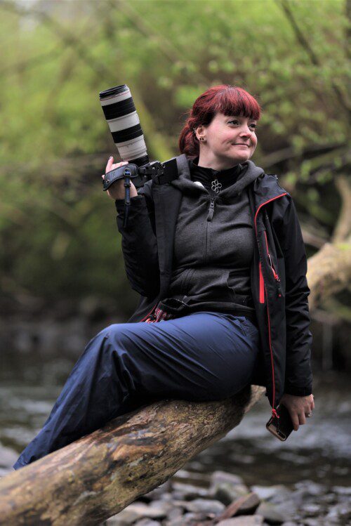 Carol, the pet photographer with a big ol camera perched on top of a fallen tree branch over water on the grounds of Glamis Castle in Scotland.