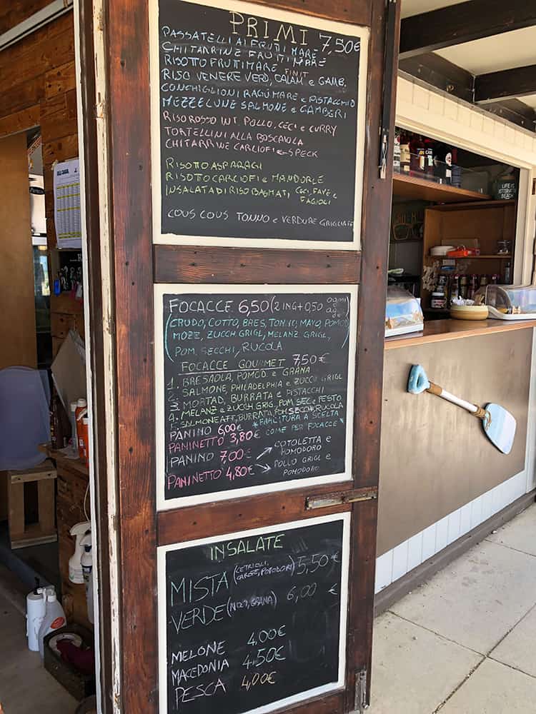 Chalkboard menu on a wall with refreshments at the dog-friendly beach in Senigallia, Italy.